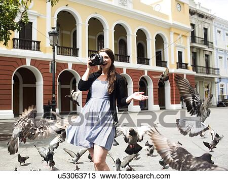 Stock Image - Puerto Rico, San Juan, woman on square among pigeons. Fotosearch