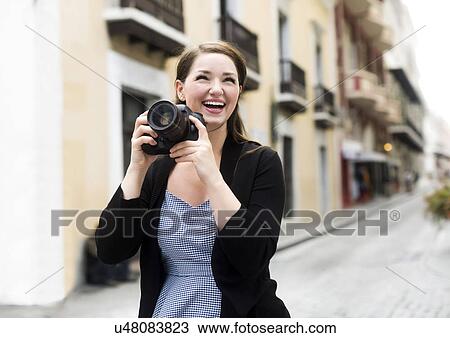 Stock Image - Puerto Rico, San Juan, Woman photographing on street. Fotosearch