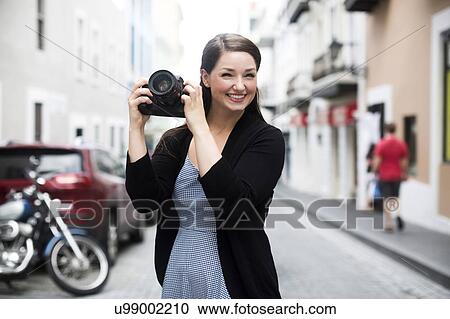 Stock Image - Puerto Rico, San Juan, Woman photographing on street. Fotosearch