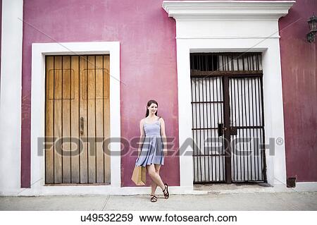 Puerto Rico, San Juan, Woman with shopping bag standing in front of pink building View Large Photo Image Stock Photo - Puerto Rico, San Juan, Woman with shopping bag standing in front of pink building. Fotosearch