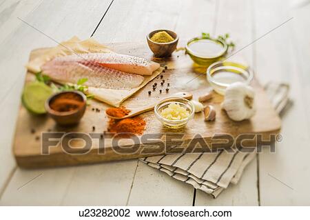 Raw tilapia and ingredients on cutting board View Large Photo Image Stock Image - Raw tilapia and ingredients on cutting board. Fotosearch