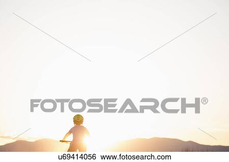 Rear view of boy (8-9) cycling at sunset View Large Photo Image Stock Photograph - Rear view of boy (8-9) cycling at sunset. Fotosearch