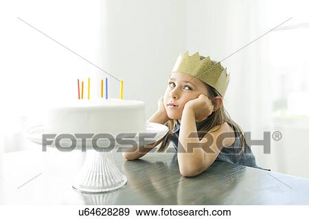 Stock Photo - Sad girl (6-7) with birthday cake. Fotosearch