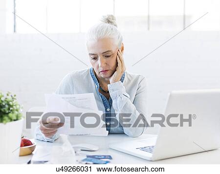 Stock Image - Senior woman paying bills. Fotosearch