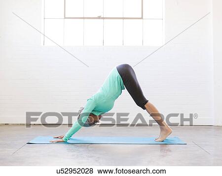 Stock Photo - Senior woman practicing yoga on mat. Fotosearch