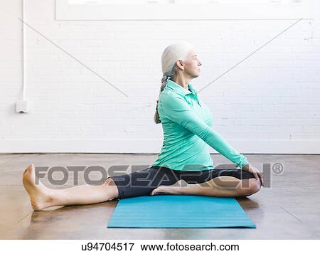 Stock Photo - Senior woman practicing yoga on mat. Fotosearch