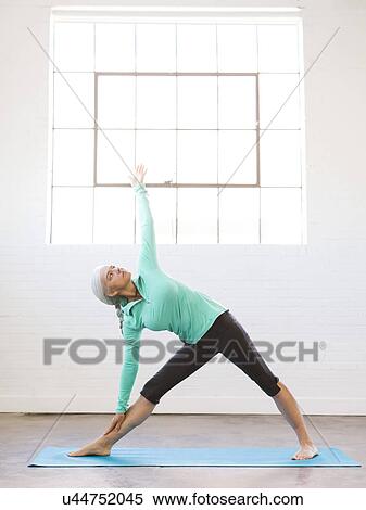 Stock Photography - Senior woman practicing yoga on mat. Fotosearch