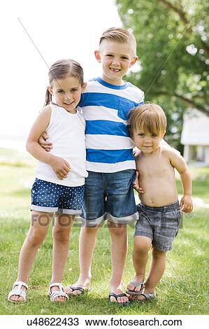 Stock Image - Siblings (2-3, 4-5, 6-7) embracing in park. Fotosearch