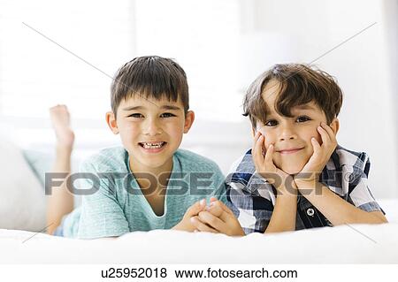Stock Photo - Siblings (6-7, 8-9) lying in bed side by side. Fotosearch