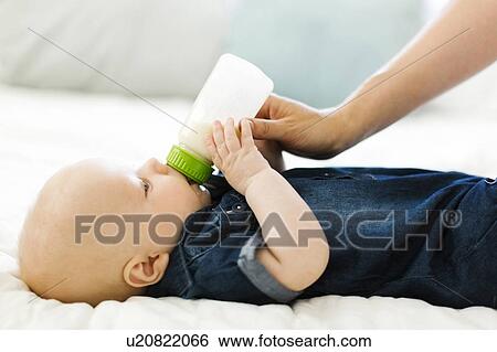 Side view of baby boy ( 12-17 months) being fed by woman with bottle of milk View Large Photo Image Stock Photograph - Side view of baby boy ( 12-17 months) being fed by woman with bottle of milk. Fotosearch