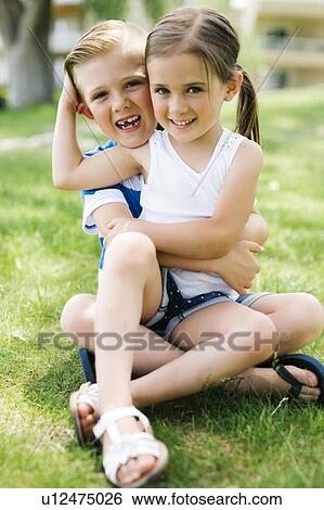Stock Photograph - Sister and brother (4-5, 6-7) embracing in park. Fotosearch