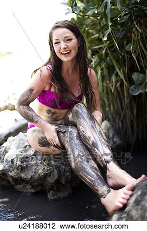 Stock Image - Sitting woman with legs covered with mud. Fotosearch