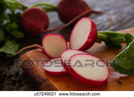 Stock Image - Slices of red radish on cutting board. Fotosearch