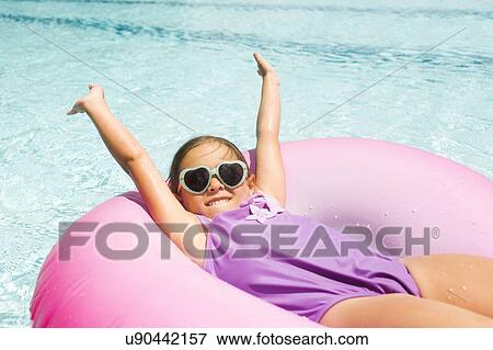 Stock Photo - Smiling girl (4-5) relaxing in inflatable ring. Fotosearch