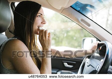 Smiling woman driving car and eating pretzel View Large Photo Image Stock Image - Smiling woman driving car and eating pretzel. Fotosearch