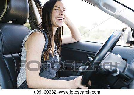 Stock Image - Smiling woman driving car. Fotosearch