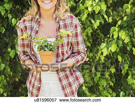 Stock Photo - Smiling woman holding potted plant. Fotosearch
