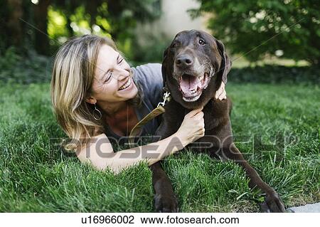 Smiling woman lying on grass with Labrador Retriever View Large Photo Image Stock Image - Smiling woman lying on grass with Labrador Retriever. Fotosearch