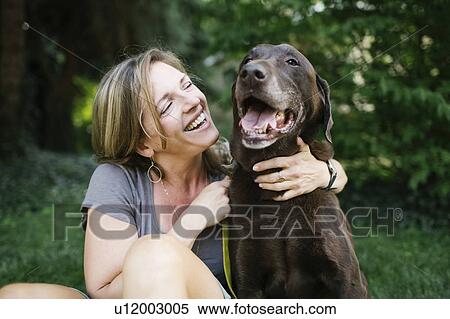 Smiling woman sitting on grass with Labrador Retriever View Large Photo Image Stock Photography - Smiling woman sitting on grass with Labrador Retriever. Fotosearch
