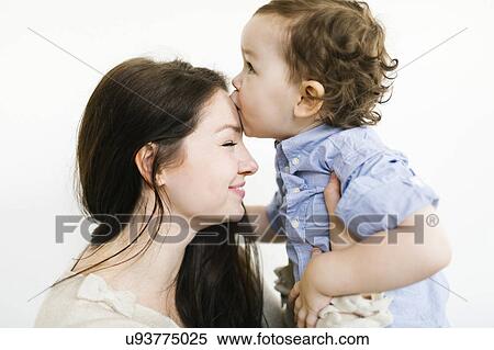 Stock Photography - Son (4-5) kissing mother's forehead. Fotosearch