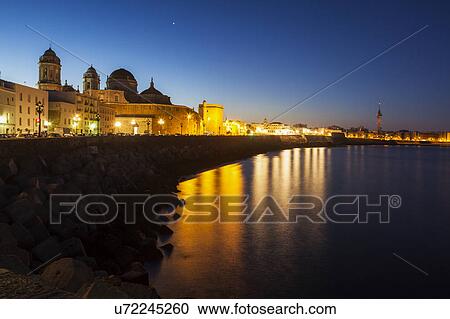 Stock Image - Spain, Andalusia, Cadiz, Cathedral de Cadiz and waterfront buildings at night. Fotosearch