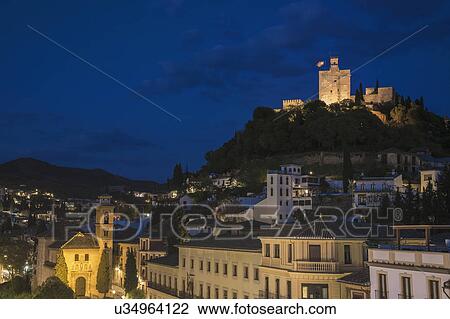 Stock Image - Spain, Andalusia, Granada, Plaza Nueva, Palace of Alhambra on hill at night. Fotosearch