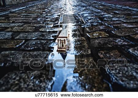 Stock Photography - Spain, Andalusia, Seville, La Macarena, Church reflecting on wet cobblestone street. Fotosearch