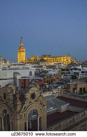 Stock Image - Spain, Seville, Cityscape with Cathedral of Seville at sunset. Fotosearch