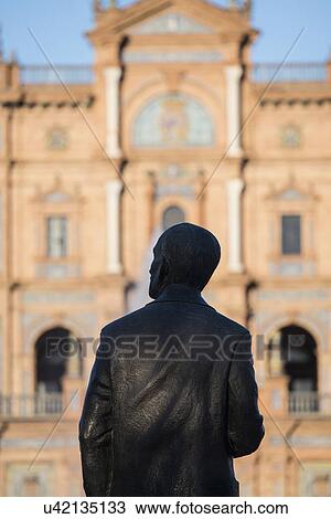 Stock Image - Spain, Seville, Plaza De Espana, Silhouette of male statue with building in background. Fotosearch