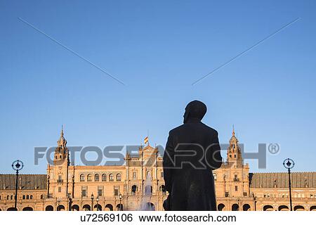 Stock Photograph - Spain, Seville, Plaza De Espana, Silhouette of male statue with building in background. Fotosearch