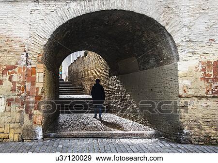 Stock Photo - Spain, Seville, Triana, Woman walking through Cajellon De La Inquisicion. Fotosearch