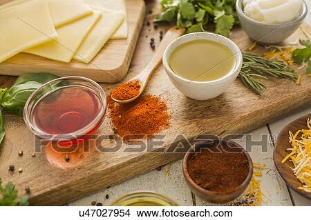 Picture - Spices, olive oil, vinegar and cheese on cutting board. Fotosearch