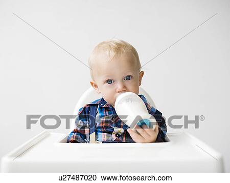 Stock Image - Studio shot of boy (12-17 months) drinking from baby bottle. Fotosearch
