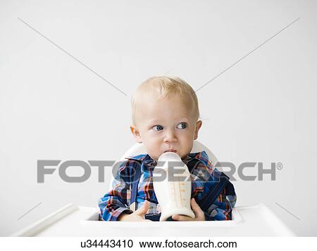 Stock Image - Studio shot of boy (12-17 months) drinking from baby bottle. Fotosearch