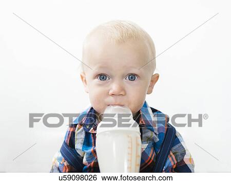 Stock Photograph - Studio shot of boy (12-17 months) drinking from baby bottle. Fotosearch