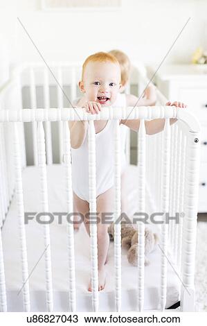 Stock Image - Twin brothers (12-17 months) standing in crib. Fotosearch