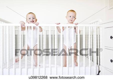 Twin brothers (12-17 months) standing in crib View Large Photo Image Stock Photo - Twin brothers (12-17 months) standing in crib. Fotosearch