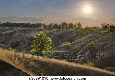 Stock Image - Ukraine, Dnepropetrovsk, Meadow with hills at sunrise. Fotosearch