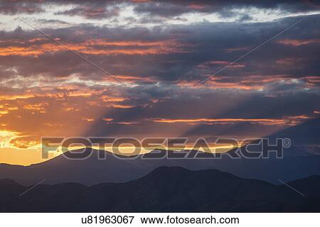 USA, Colorado, Denver, Setting sun shining through clouds over Front Range View Large Photo Image Stock Photo - USA, Colorado, Denver, Setting sun shining through clouds over Front Range. Fotosearch