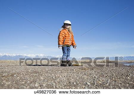 Stock Photograph - USA, Colorado, Little girl (4-5) dressed in orange padded jacket and flat cap. Fotosearch