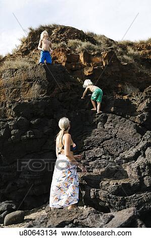 USA, Hawaii, Kauai, Mother with sons (4-5, 8-9) climbing on rocks View Large Photo Image Picture - USA, Hawaii, Kauai, Mother with sons (4-5, 8-9) climbing on rocks. Fotosearch