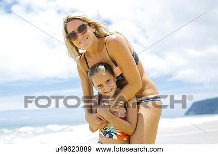 Stock Photo - USA, Hawaii, Kauai, Mother with daughter (6-7) playing on beach. Fotosearch
