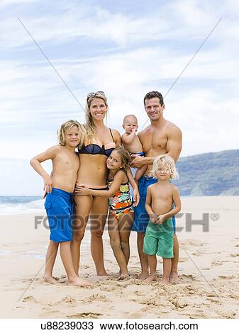 Stock Image - USA, Hawaii, Kauai, Parents with four children (12-17 months, 4-5, 6-7, 8-9) at beach. Fotosearch