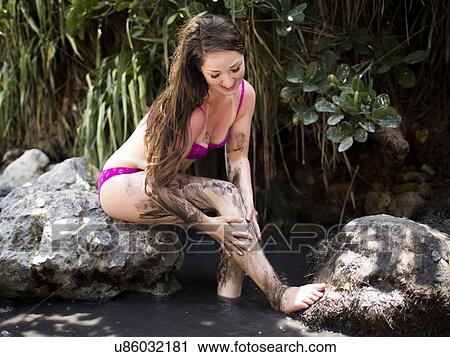 Stock Image - USA, Hawaii, Kauai, Woman applying mud on her skin. Fotosearch