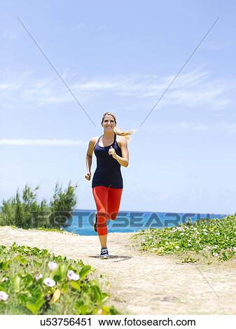 Stock Image - USA, Hawaii, Kauai, Woman jogging on beach. Fotosearch
