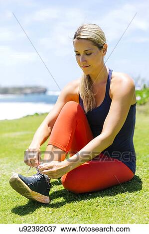 USA, Hawaii, Kauai, Woman sitting on lawn and lacing shoes View Large Photo Image Stock Photo - USA, Hawaii, Kauai, Woman sitting on lawn and lacing shoes. Fotosearch