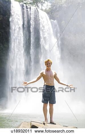 USA, Hawaii, Kauai, Young man standing on boulder in front of waterfall View Large Photo Image Stock Image - USA, Hawaii, Kauai, Young man standing on boulder in front of waterfall. Fotosearch
