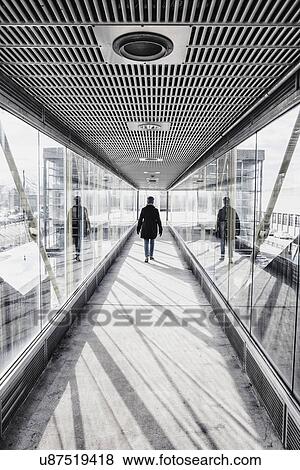 USA, Massachusetts, Boston, Woman walking down glass and metallic walkway at train station View Large Photo Image Stock Photo - USA, Massachusetts, Boston, Woman walking down glass and metallic walkway at train station. Fotosearch