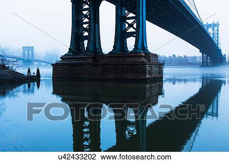 Stock Image - USA, New York, New York City, Manhattan, Brooklyn Bridge over East River in fog. Fotosearch
