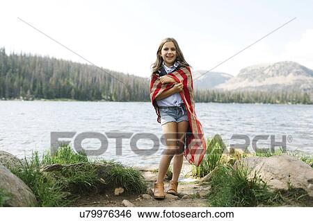 Stock Photograph - USA, Utah, Midway, Portrait of girl (8-9) wrapped in us flag standing by lake. Fotosearch